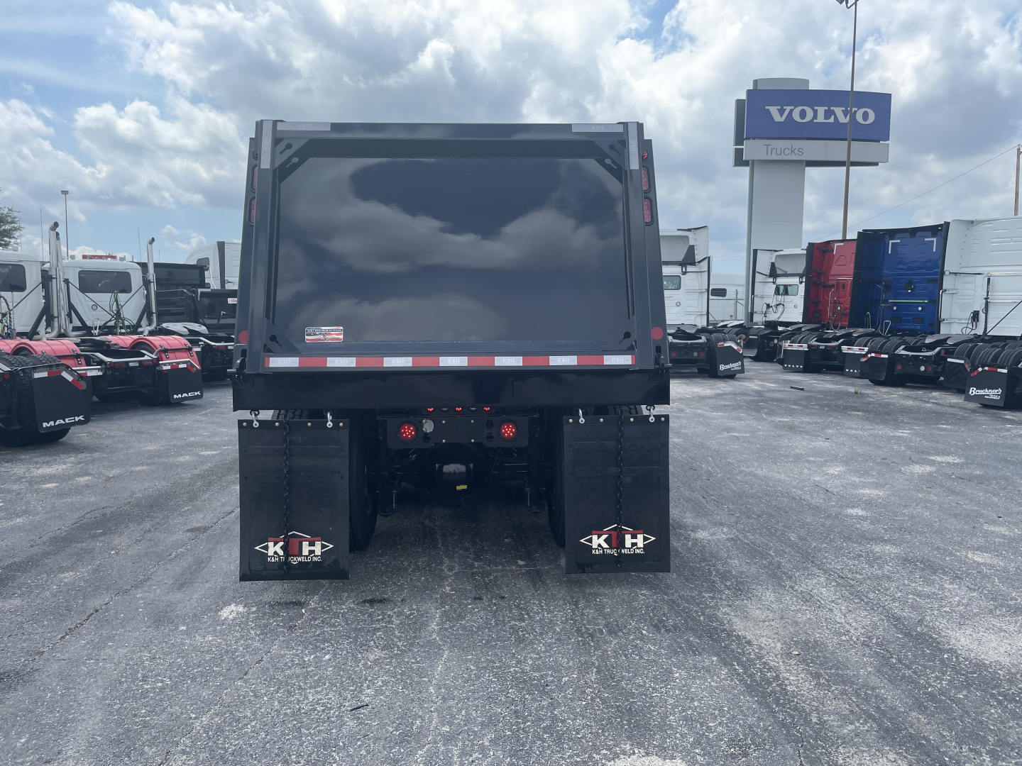Volvo VHD64F300 dump truck rear showing dump bed, taillights, and mud flaps with KH logo.