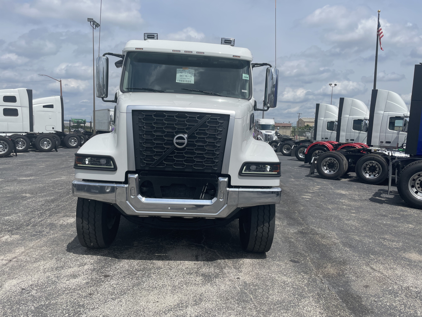 Front view of a new Volvo VHD64F300 dump truck with bold black grille and headlights, Volvo emblem on the grille, in a dealership lot.