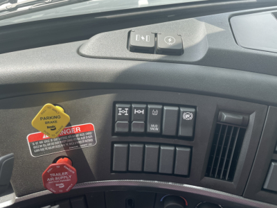 Cab interior of Volvo truck showing dashboard switches including parking brake, hazard, blank switches, and red trailer air supply knob.
