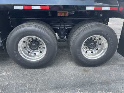 Dual rear wheels on a Volvo VHD64F300 dump truck showing tires, suspension, and undercarriage with chrome rims.