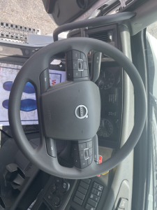 Steering wheel and dashboard of a Volvo VHD64F300 truck interior showing steering wheel controls and instrument cluster.