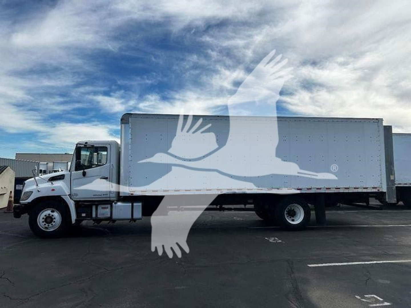 Commercial truck in a parking lot showing a white box truck with a gray cargo box and a watermark overlay. No legible labels visible on cab or box.