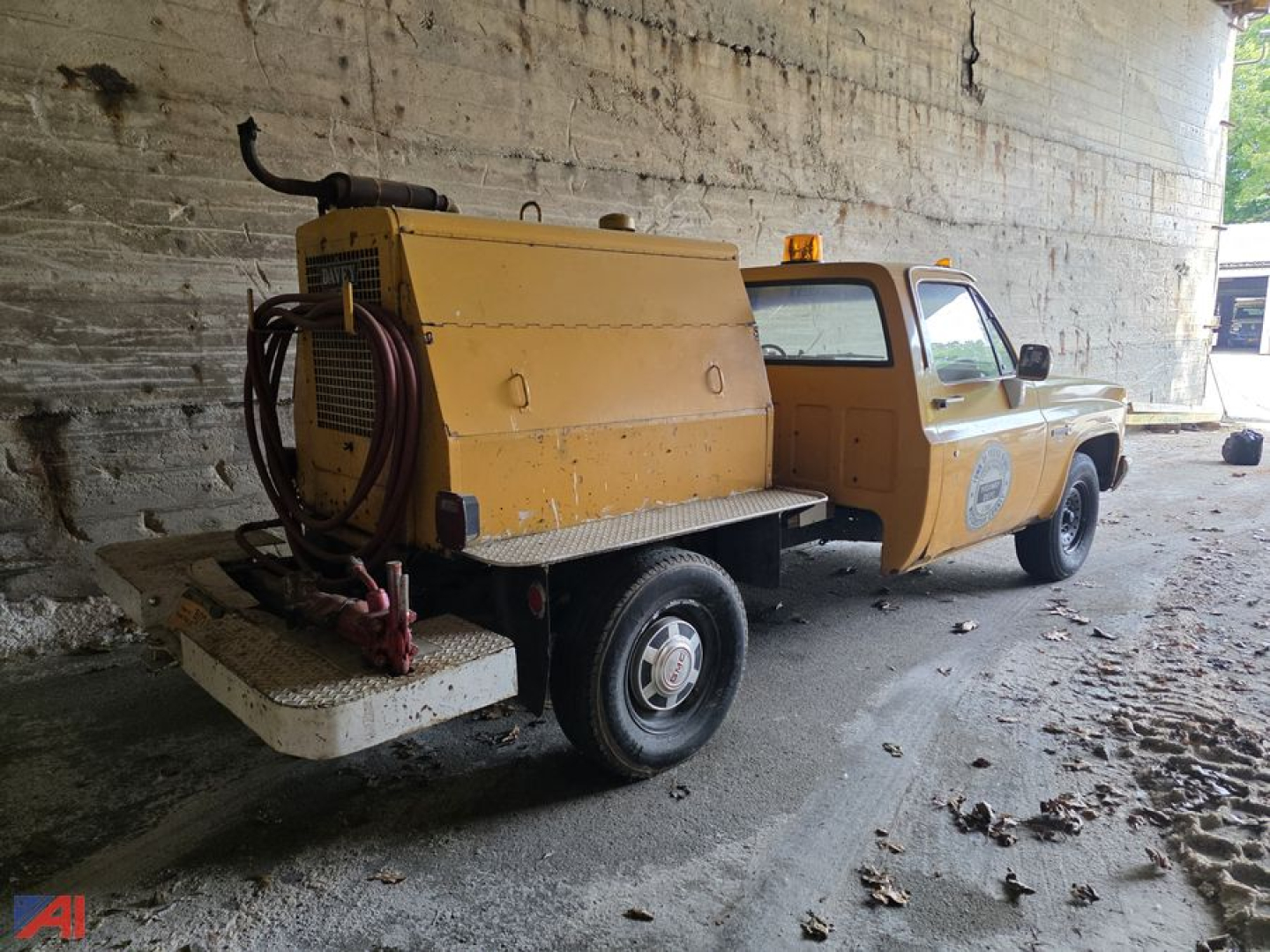 GMC C/K 2500 series pickup with a large yellow vacuum or service tank mounted in bed, single cab, two-wheel drive, rear view showing side of truck