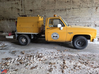 GMC C/K 2500 series pickup with yellow utility body and emblem on door, side view showing front cab and rear service unit with tank, in a garage.
