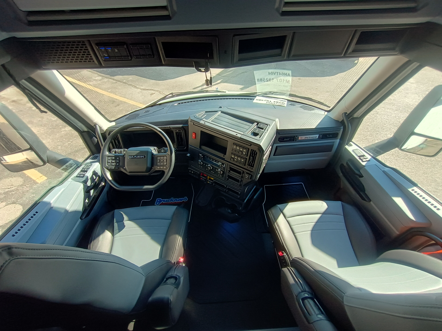 Truck cab interior of a 2027 Mack AN64T64 with steering wheel, dashboard, seats visible and windshield view