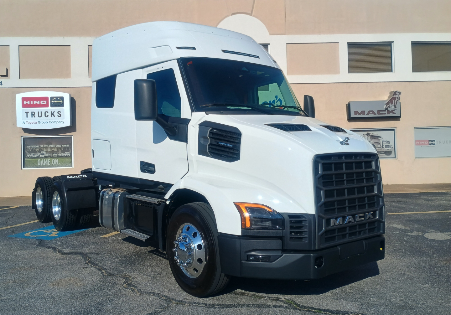 Mack AN64T64 conventional sleeper truck showing front grille and cab side with white paint and chrome wheels.