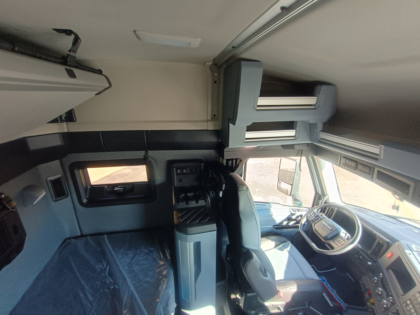 Cab interior of a 2027 Mack AN64T64 truck showing driver's seat, dashboard, overhead storage compartments, and sleeper area.