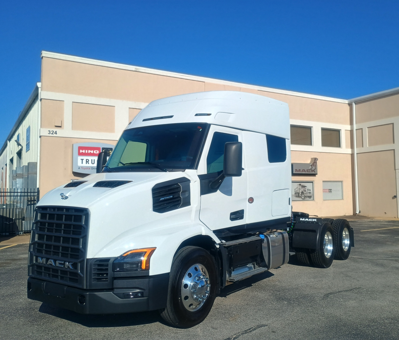 White Mack AN64T64 tractor-trailer truck in a yard showing front grille with MACK badge, side fuel tanks, and dual rear axles.