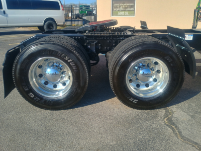 Dual rear truck wheels showing polished chrome rims and Bridgestone tires, part of a Mack AN64T64 chassis with fifth wheel and frame components visible.