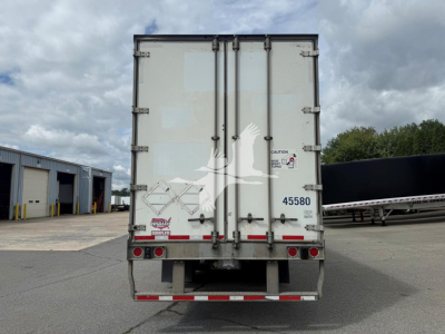 Back of a 2017 Wabash dry van trailer showing rear doors with safety decals, handle bars, and taillights. Visible text includes stock tag 45580, caution label, and company decals.