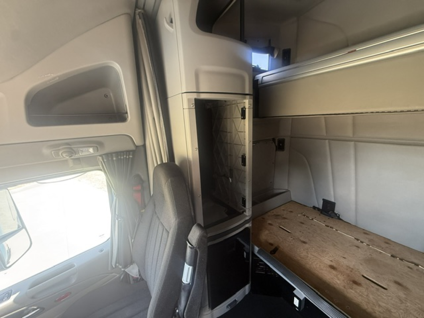 Peterbilt 579 cab interior showing sleeper area and storage cabinets with exposed plywood floor panel.