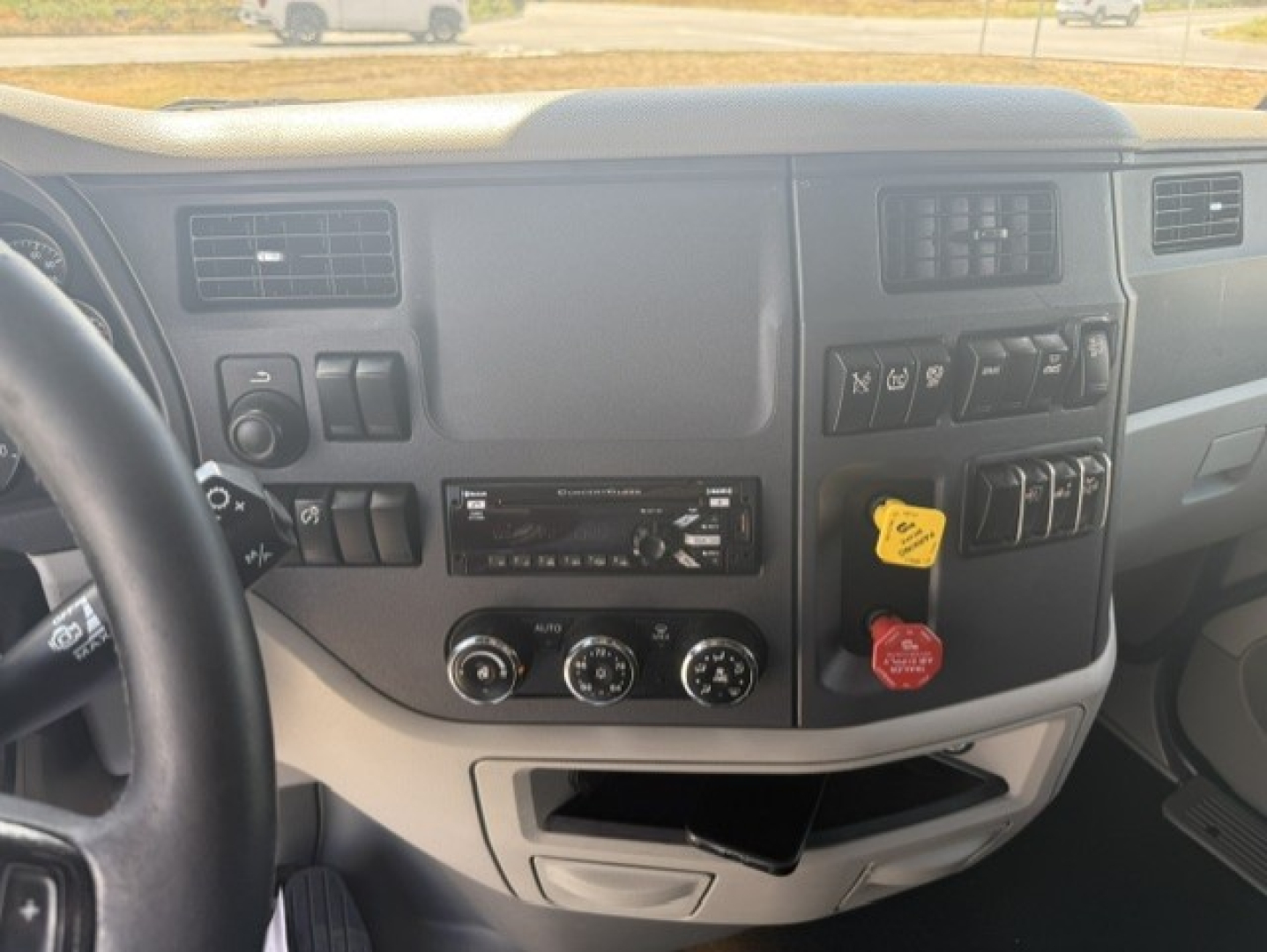 Peterbilt 579 dash view showing steering wheel, instrument panel, HVAC controls, dashboard switches, and yellow key tag in ignition.