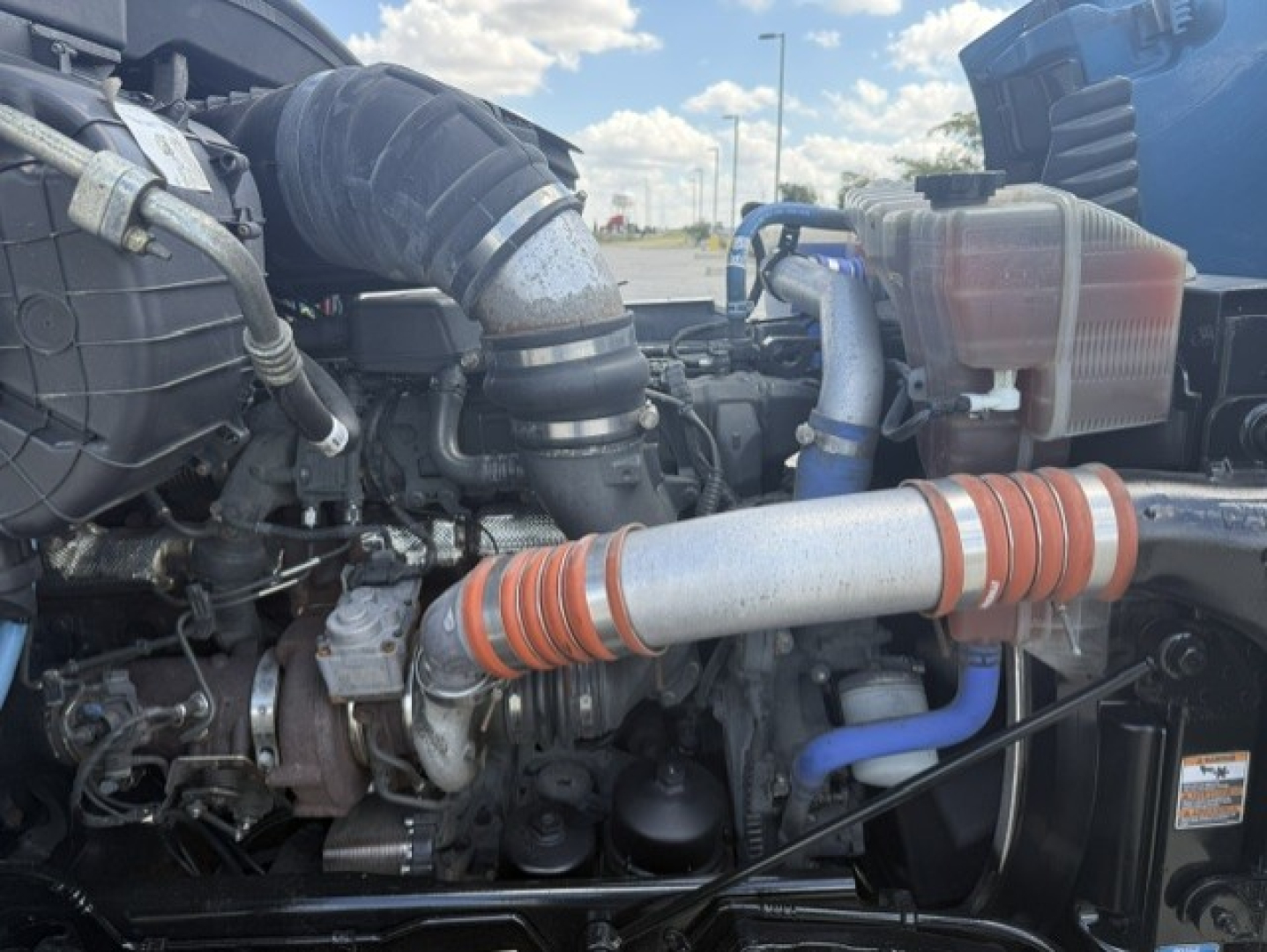 Peterbilt 579 engine bay showing intake hose, intercooler, coolant reservoir, and turbo piping.