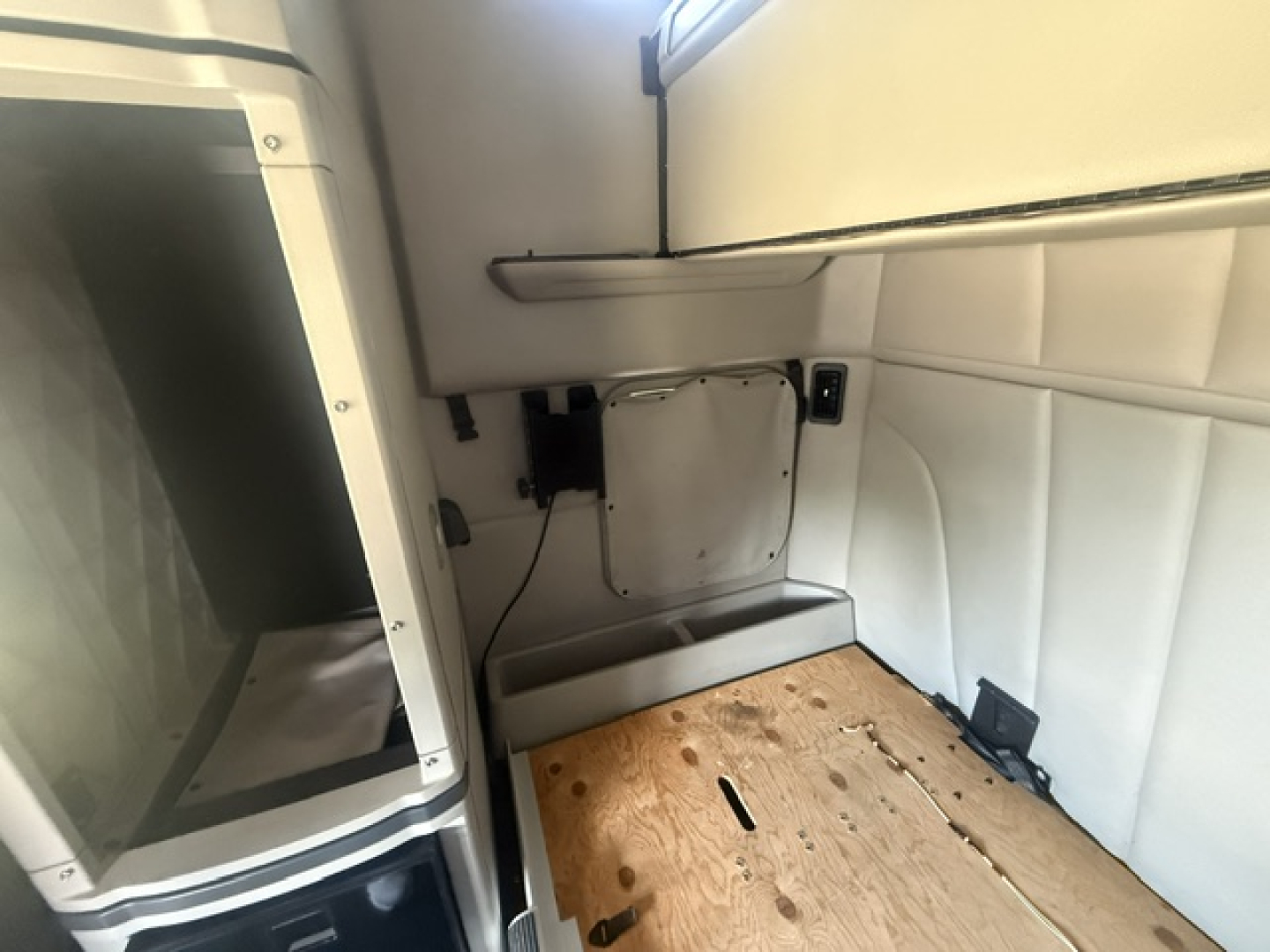 Peterbilt 579 sleeper cab interior cargo area with wooden floor panel and side paneling.