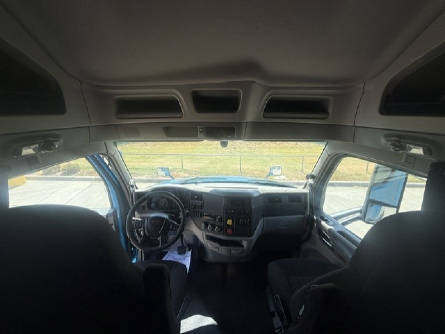 Peterbilt 579 truck interior cab view from back seat, dashboard with steering wheel and center console.