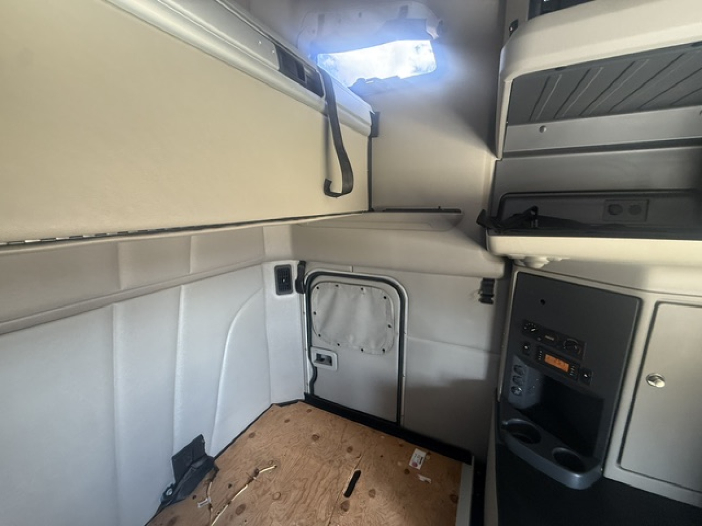 Truck cab interior showing sleeper area and side door with small vent; no visible labels or brand markings in this view.