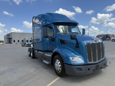 Peterbilt 579 truck in blue, front three-quarter view. Visible: grille, headlights, side mirrors, sleeper cab, chrome wheels, fuel tanks, and steps.