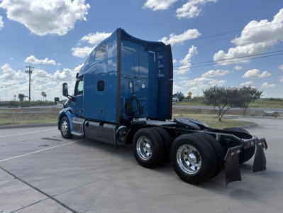 Peterbilt 579 conventional sleeper tractor in blue, side rear view showing tractor chassis and rear axles, no cab interior visible.