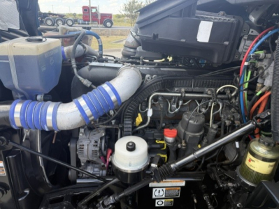 Peterbilt 579 engine bay showing coolant reservoir, hoses, and intake with various fluid reservoirs and wiring.