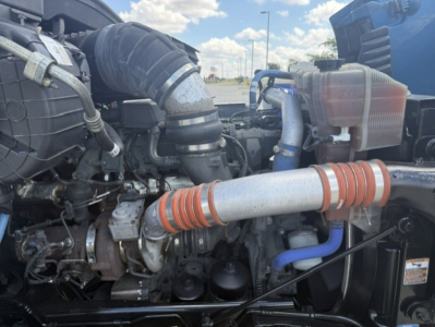 Peterbilt 579 engine bay showing intake hose, intercooler, coolant reservoir, and turbo piping.