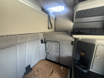 Truck cab interior showing sleeper area and side door with small vent; no visible labels or brand markings in this view.