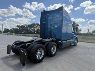 Peterbilt 579 semi-truck tractor rear view showing blue cab, dual rear axles, and fifth-wheel hitch area.