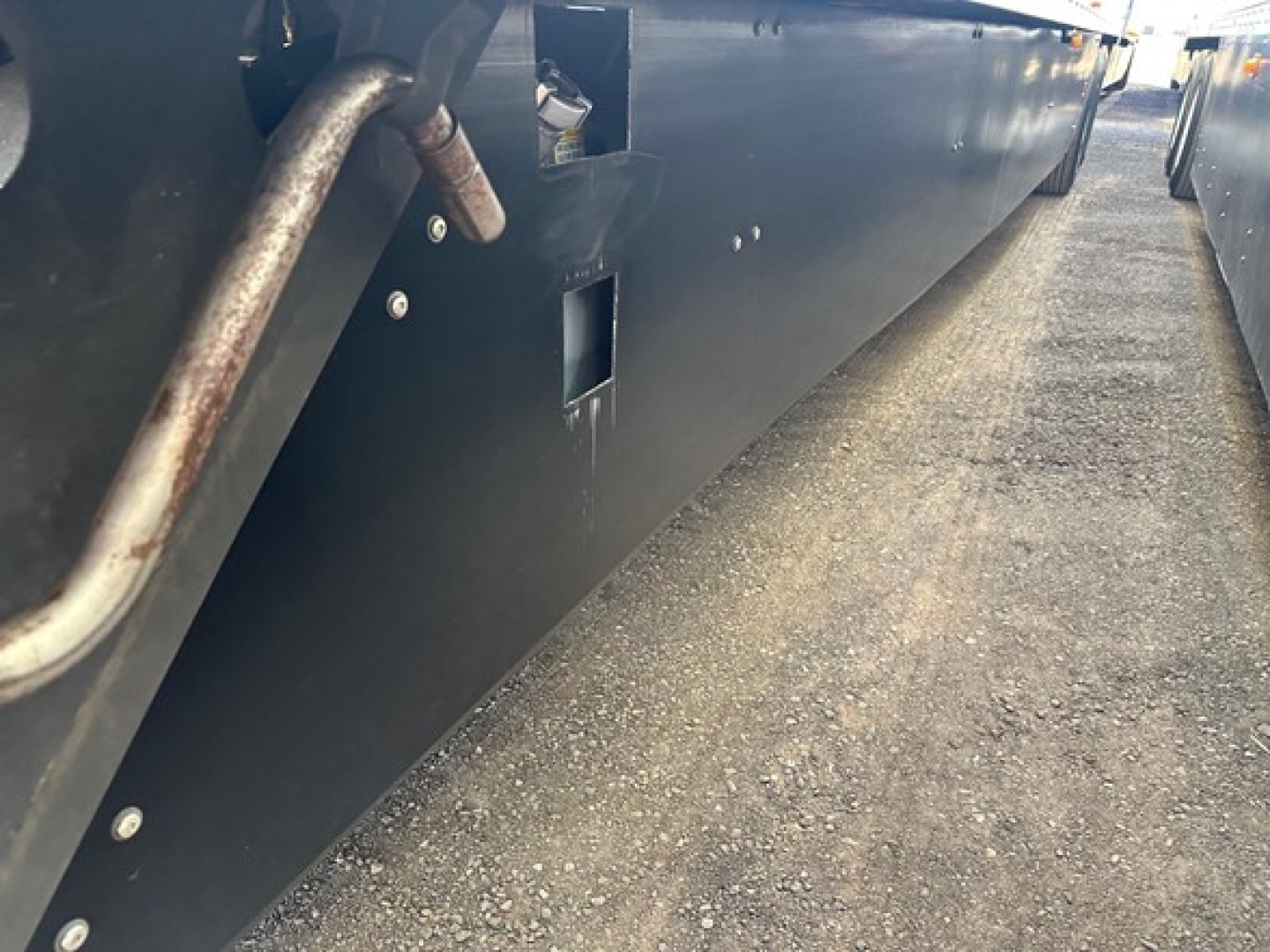 Reefer trailer side view showing lower side panel with drain/valve opening and metal piping.