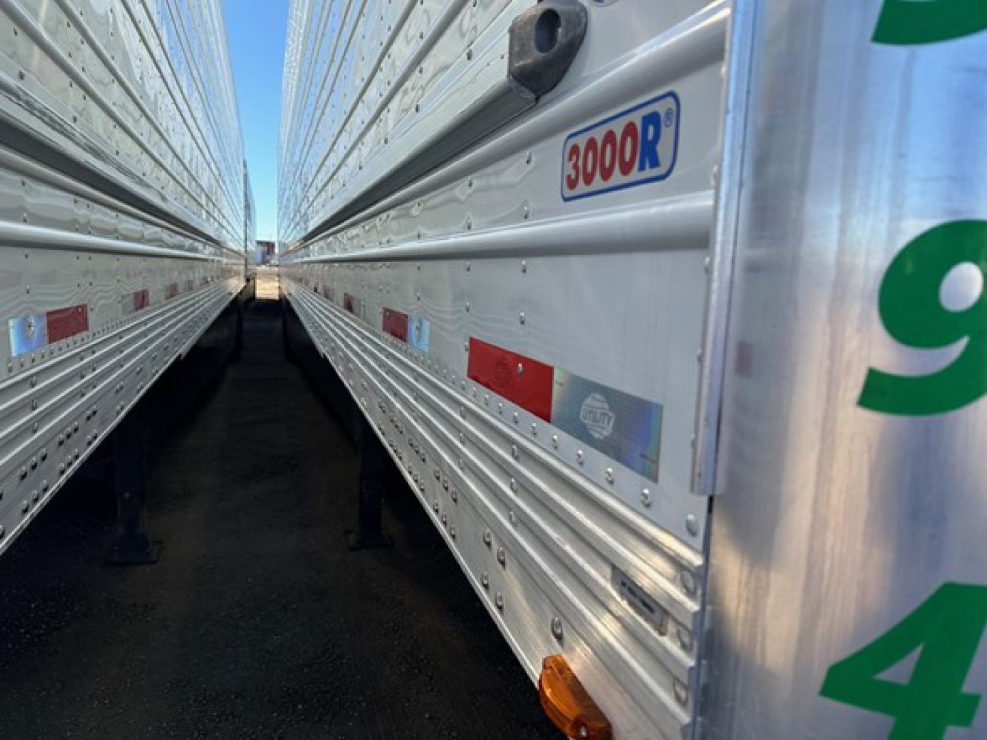 Reefer trailer side view showing 300R sticker and aluminum siding with rivets, between two trailers in a yard.