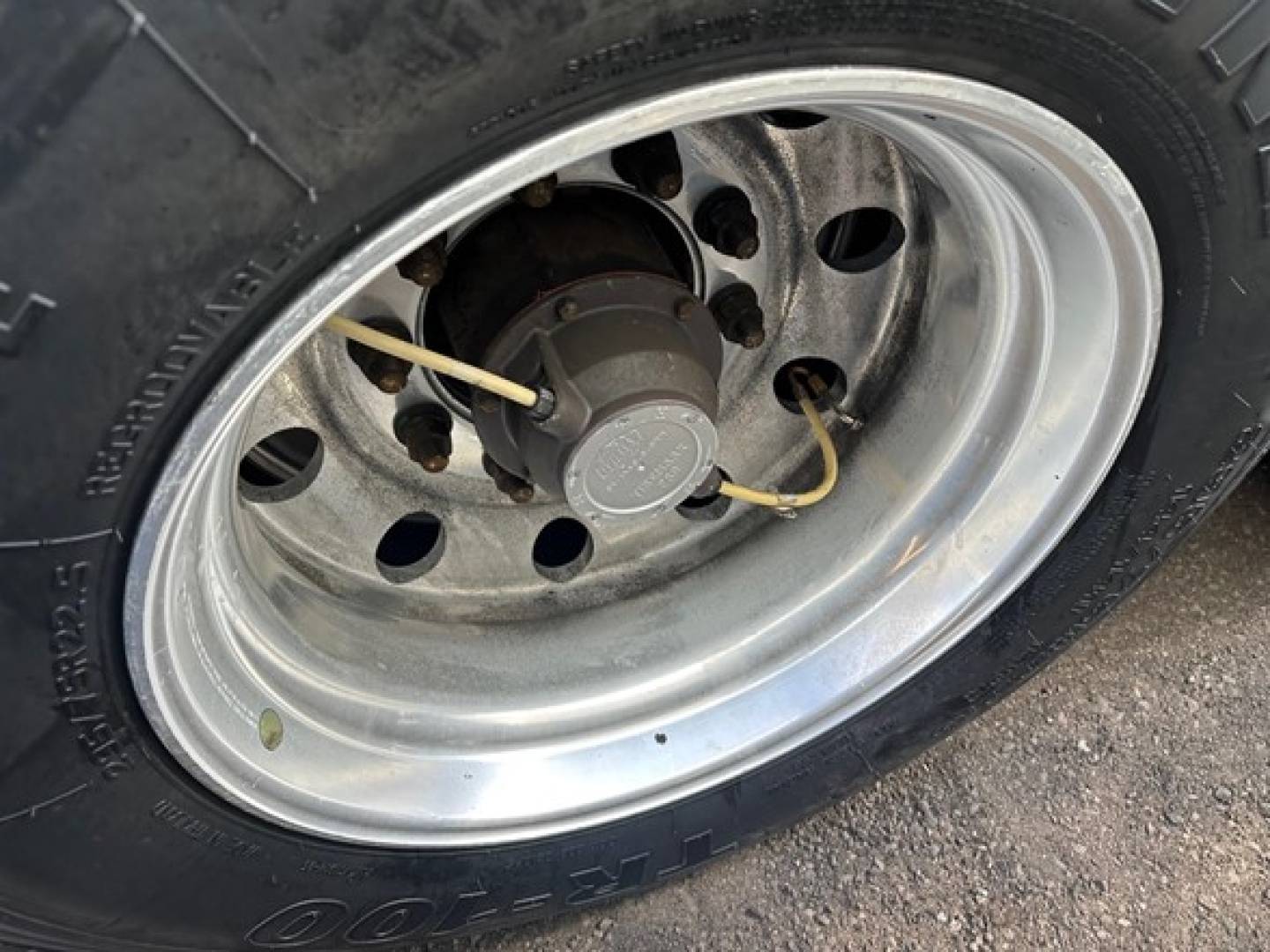 Trailer wheel showing polished steel rim and tire with valve stem and hub cap visible