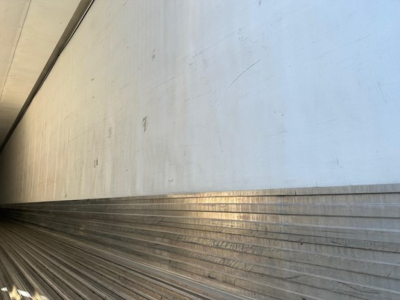 Trailer interior side wall and floor edge with ribbed metal flooring and aluminum wall, long perspective