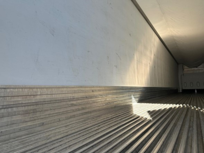 Trailer interior showing ribbed metal floor and side wall; empty reefer trailer interior.