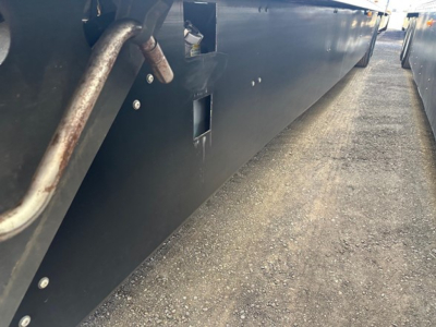 Reefer trailer side view showing lower side panel with drain/valve opening and metal piping.