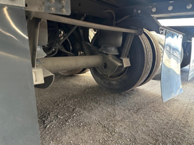 Reefer trailer undercarriage showing suspension beam and wheel with drum brake, mud flaps visible.