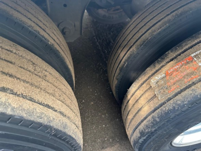 Close-up of a trailer rear dual tires with dirt and wear, showing sidewall treads and a red/orange label on the right tire.