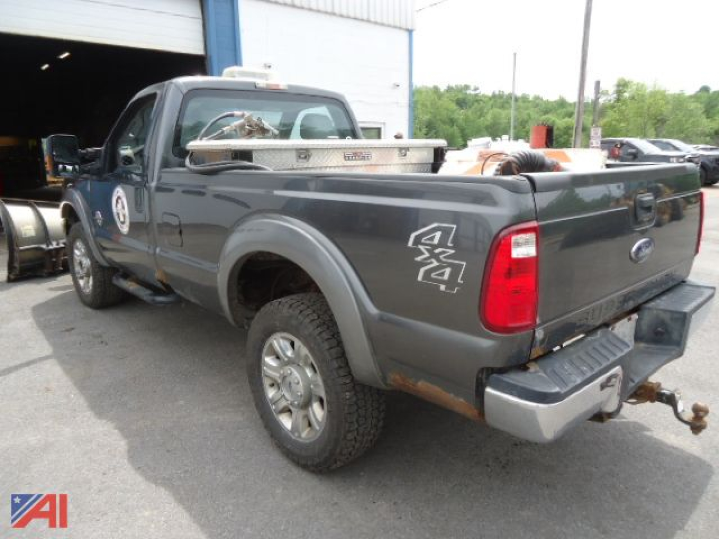 Ford F-350 Super Duty pickup with plow seen from rear-left side, dual rear wheels, 4x4 badges, field work truck setup.