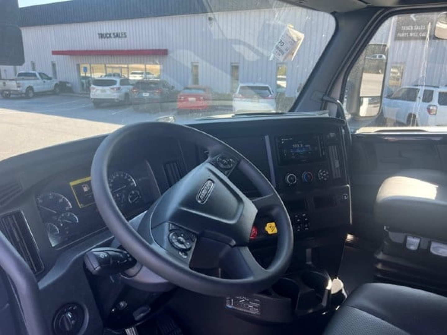 Interior of a Freightliner Cascadia cab showing steering wheel, dashboard, and center console with gauges and controls.