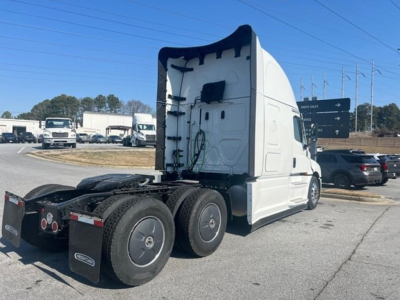 Freightliner Cascadia tractor rear view showing sleeper cab, seventh wheel, and rear tires; white exterior with exposed roof fairing.