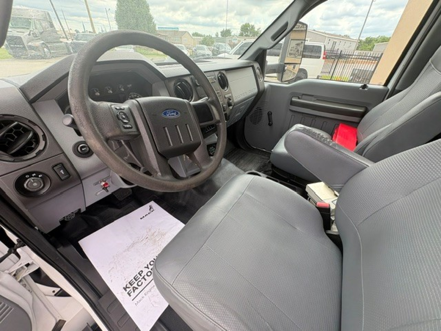 Ford F-750 cab interior showing steering wheel with Ford emblem, dashboard, and front seats.