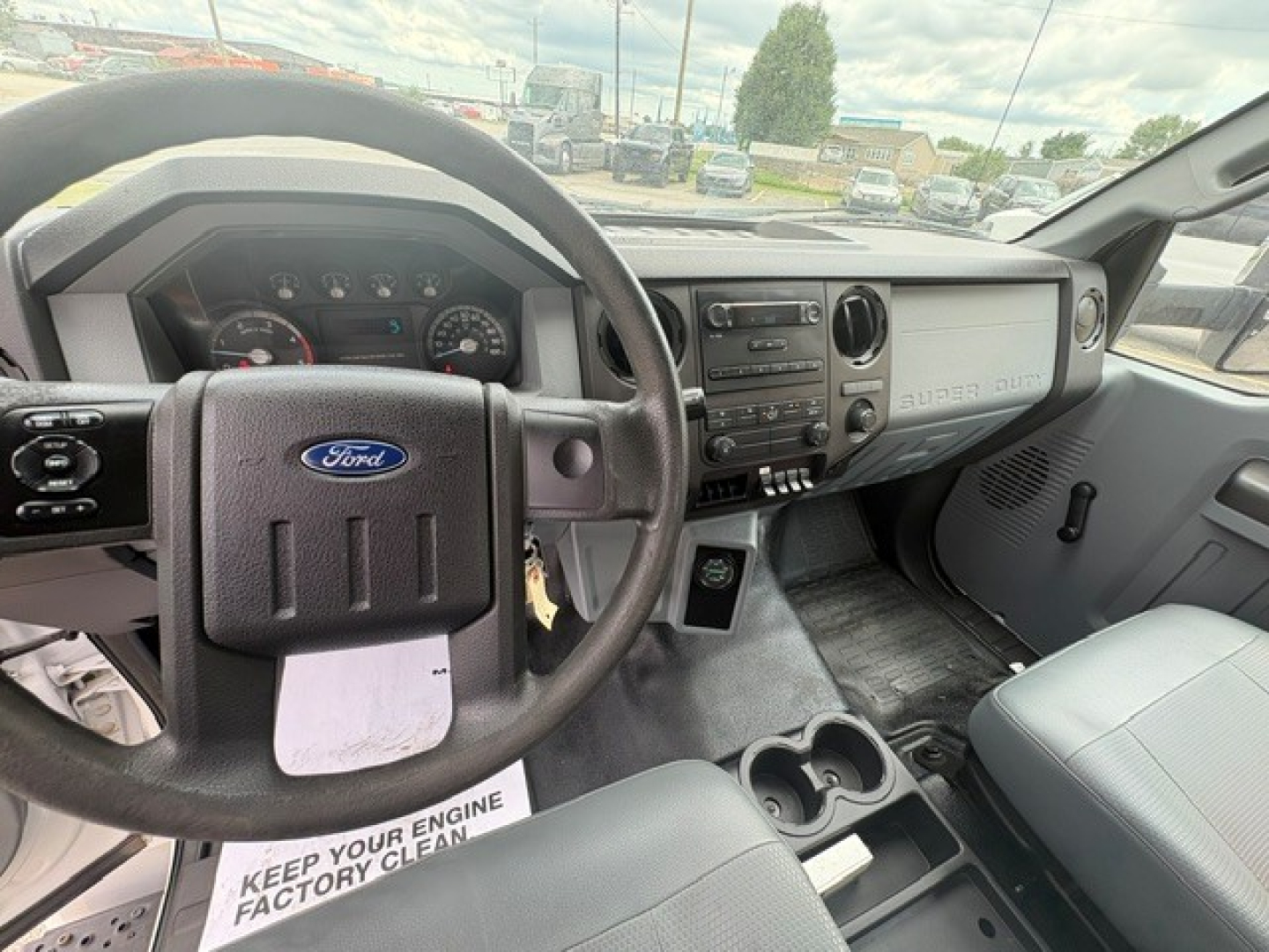 Ford F-750 cab interior showing steering wheel with Ford emblem, dashboard, center console, and gear shifter with cup holders.