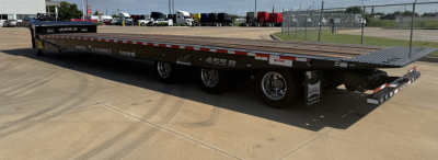 Traveling axle trailer showing Landoll 455B-53 55-ton lowboy with black deck and dual rear wheels, side lettering, and safety railing end.