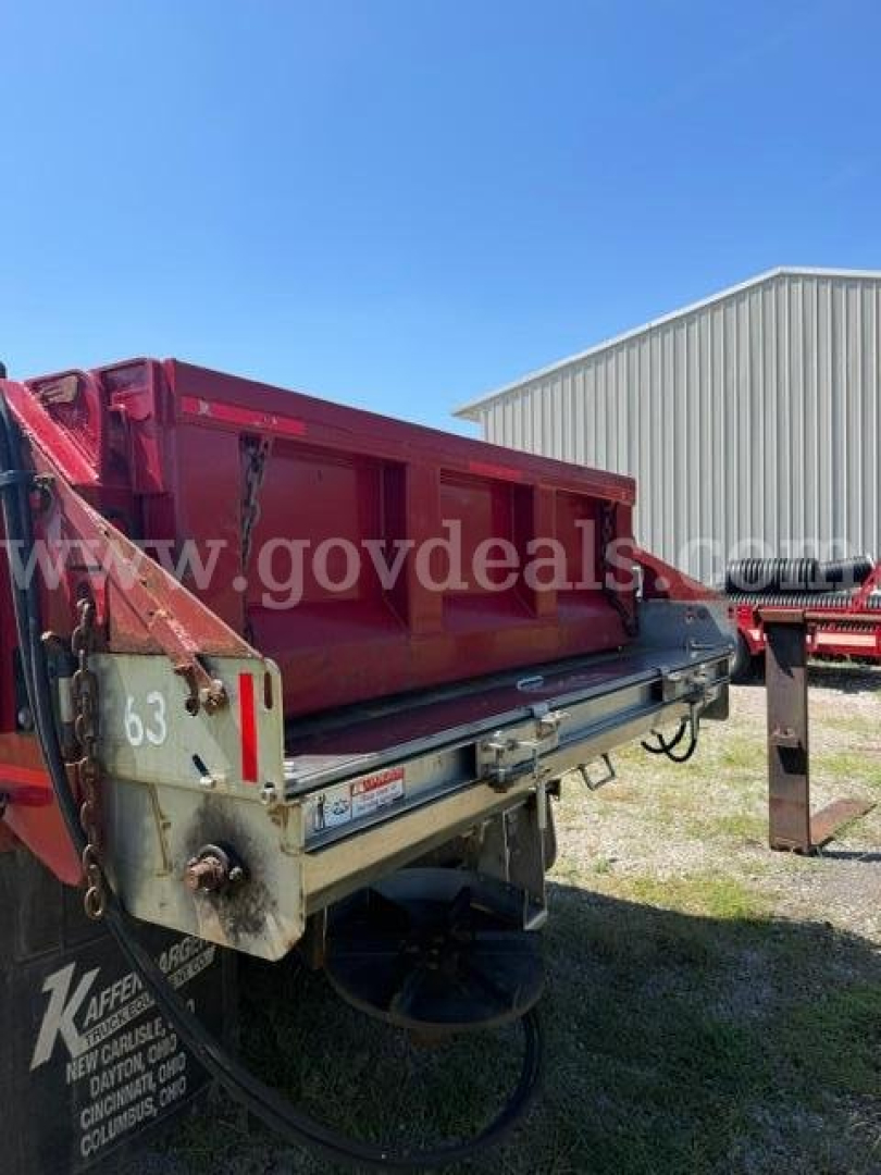Truck bed of a plow truck showing red dump bed attached to a chassis with hydraulic lines and metal framework.