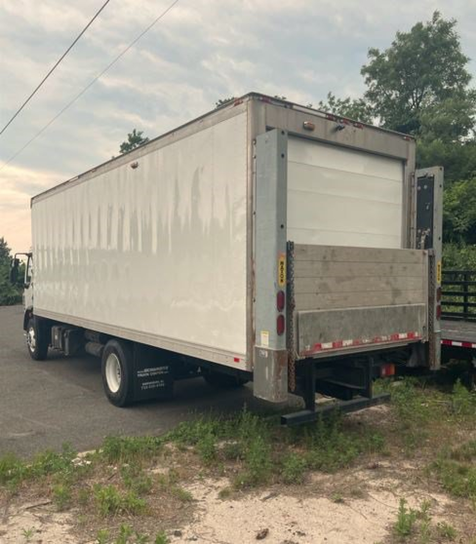 Kenworth reefer truck box rear view showing cargo trailer with liftgate and reflective tape. Visible text on side includes small white lettering near wheels and rear bumper area.