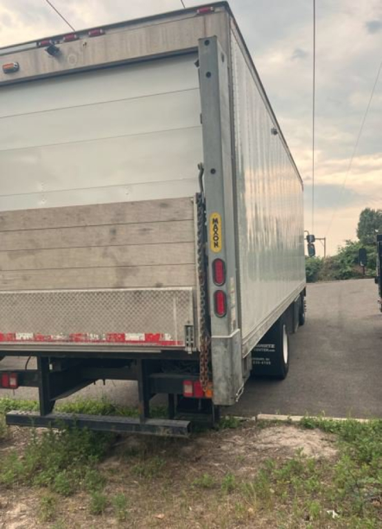 Kenworth COE Reefer Truck rear view showing cargo trailer with metal siding, bumper steps, and rear lights; visible wheel and side door area.