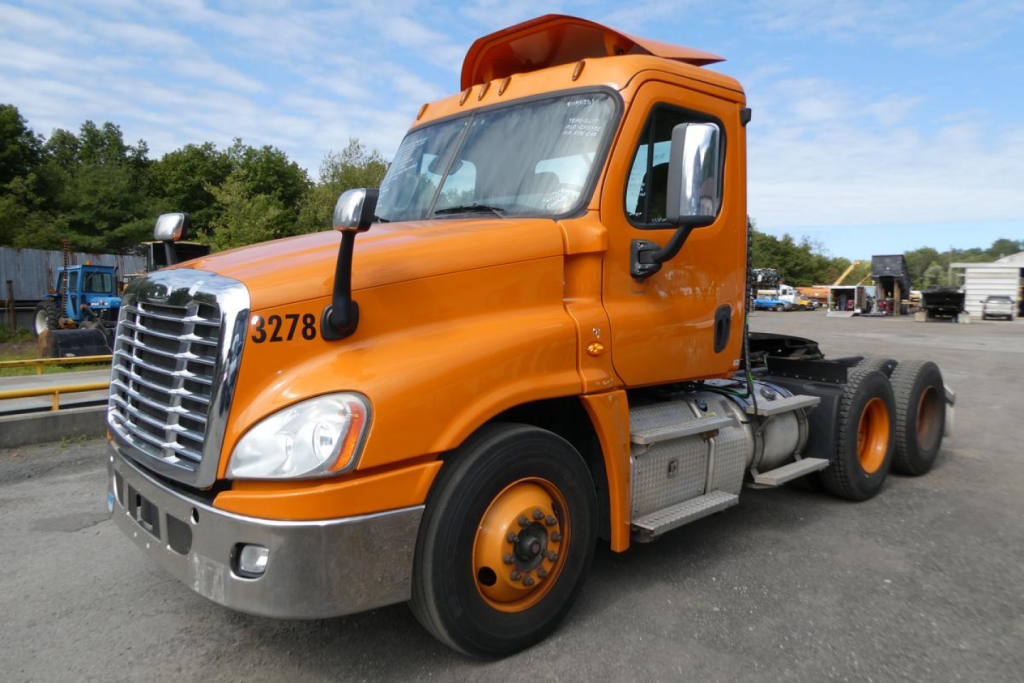 Orange Freightliner Cascadia 125 daycab truck in a lot with 6x4 axle configuration and black chassis; cab number 3278 visible.