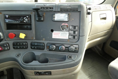 Dashboard of a Freightliner Cascadia 125 daycab interior with control panel, gauges, vents, and cup holders.