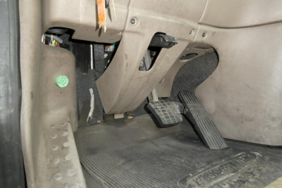 Cab area showing pedals and footwell of a Freightliner Cascadia 125 daycab, with accelerator and brake pedals visible and dashboard panels nearby.