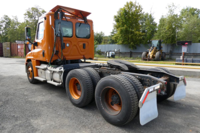 Orange Freightliner Cascadia 125 cab?tractor rear view showing dual rear axles and mud flaps.