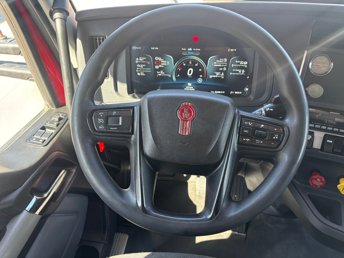 Kenworth T680 steering wheel and dashboard view showing digital gauges and steering controls.