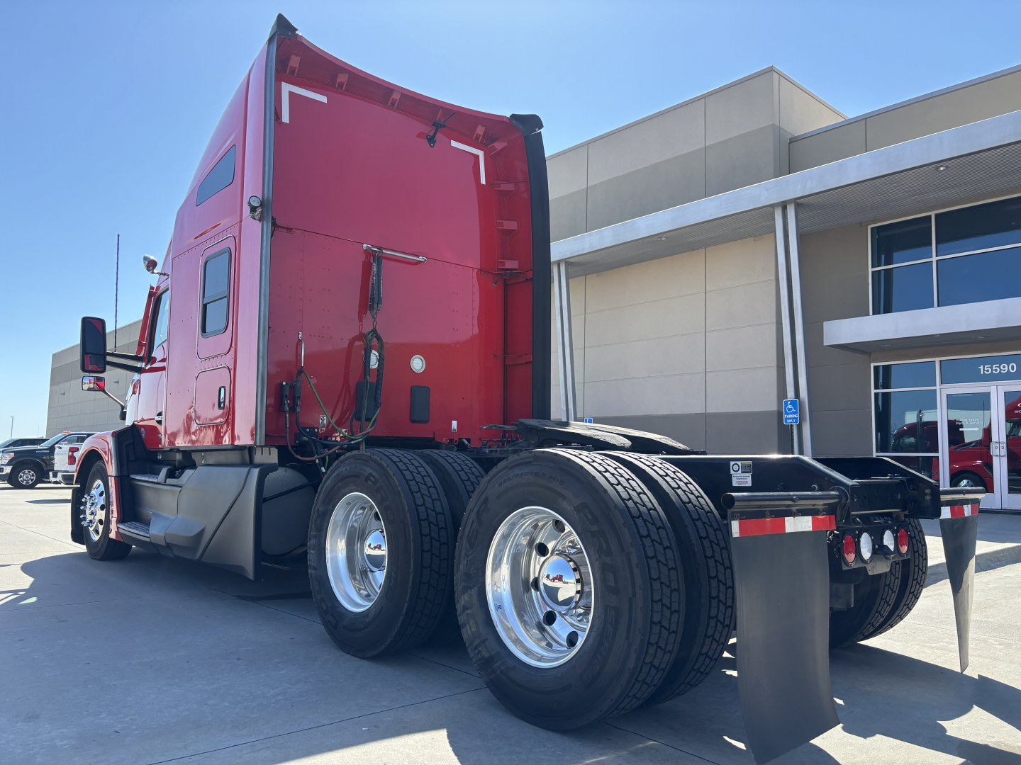 Kenworth T680 truck rear and side view showing dual rear axle/sets with red cab and chrome wheels. Visible text includes no obvious labels in view.