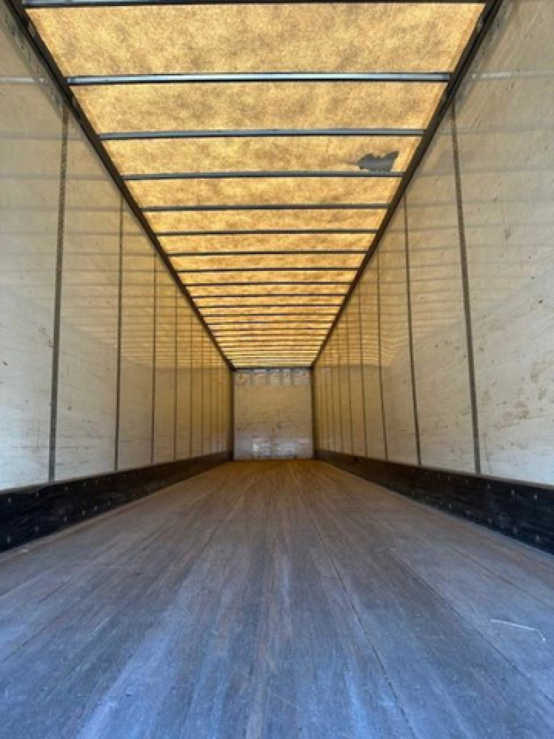 Trailer interior showing long van box with wooden roof panels and side walls, empty cargo area.